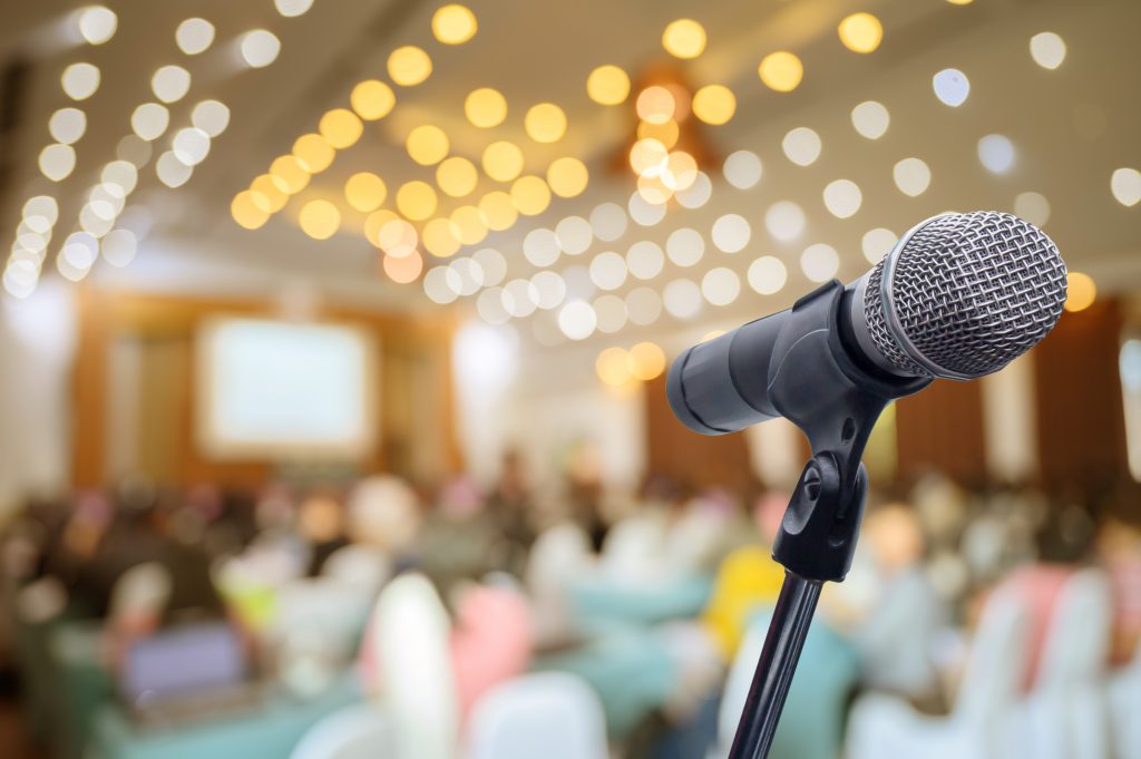 Wystąpienia publiczne z perspektywy psychologicznej 5 wystąpienia publiczne – zdjęcie mikrofonu na pierwszym planie, w tle sala